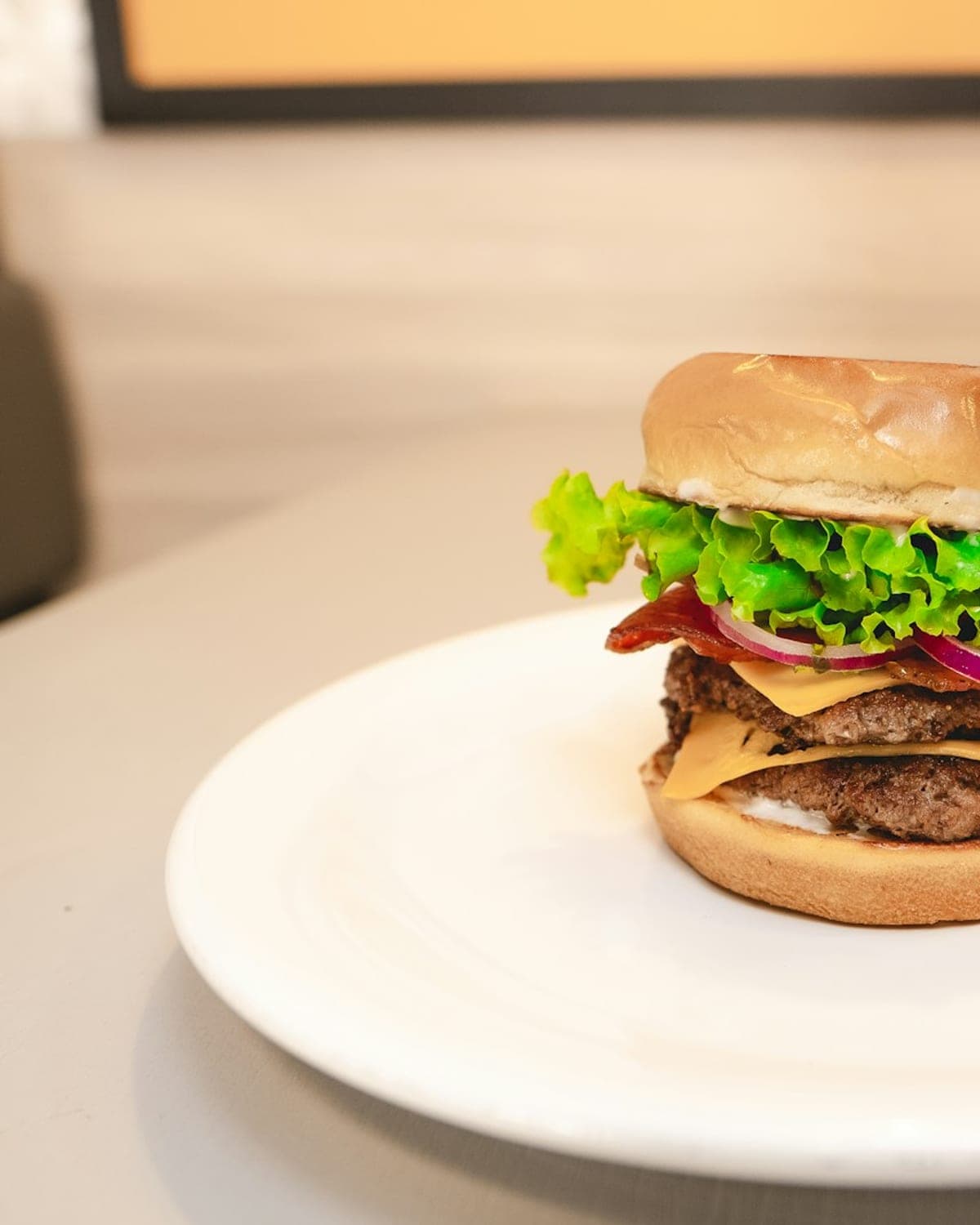 Close-up van een smashburger met gesmolten cheddar, augurk en rode ui tussen een sesambroodje.