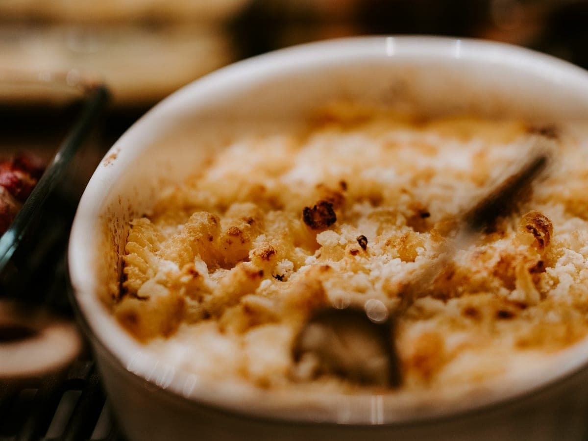 Een gietijzeren pan mac and cheese met een goudbruine, krokante kaaskorst.